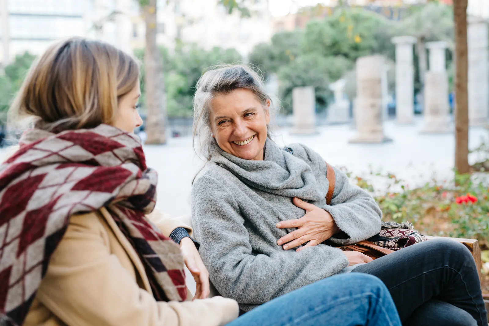 Two women laughing together on a park bench